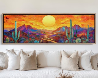 May include: A panoramic landscape painting depicting a desert scene with a large sun setting over a winding river and mountains in the distance. The painting is framed in a wooden frame and is hanging on a white wall above a white sofa.