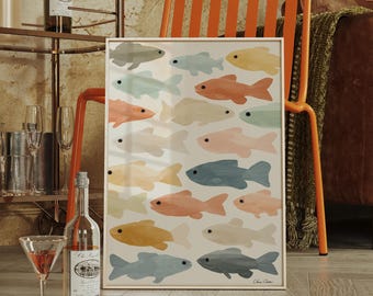 May include: A framed art print featuring a pattern of colorful fish in shades of peach, blue, yellow, and gray. The artwork is displayed against a neutral background. The print is propped up against an orange chair, with a brown leather sofa in the background.