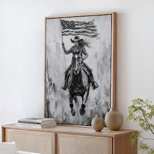 Könnte beinhalten: Schwarzweiß-Leinwanddruck einer Frau, die ein Pferd reitet, mit einer amerikanischen Flagge im Hintergrund.