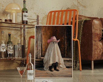 Può includere: Un'opera d'arte incorniciata raffigura un fantasma con un cappello da cowboy rosa e stivali. L'opera d'arte è esposta in una stanza con un carrello bar, un divano in pelle e una sedia arancione. Una bottiglia di vino e un bicchiere da martini sono in primo piano.