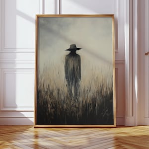 Peut inclure: Une &oelig;uvre d'art encadr&eacute;e repr&eacute;sente une silhouette portant un chapeau dans un champ d'herbes hautes. L'&oelig;uvre est r&eacute;alis&eacute;e dans des tons sourds de gris, de brun et de beige, avec une qualit&eacute; douce et atmosph&eacute;rique. Le cadre est de couleur bois clair.