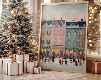Puede incluir: Una impresión enmarcada representa una escena invernal nevada con casas adosadas coloridas y gente patinando sobre hielo. A la izquierda hay un árbol de Navidad con adornos dorados y luces de cadena. Cajas de regalo blancas con cinta dorada en primer plano.