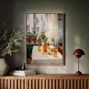 Puede incluir: Una pintura al óleo enmarcada representa una naturaleza muerta con una mesa puesta para una comida. La mesa está cubierta con un mantel blanco y presenta botellas, vasos y un cuenco de naranjas. El fondo incluye una ventana con plantas y flores.
