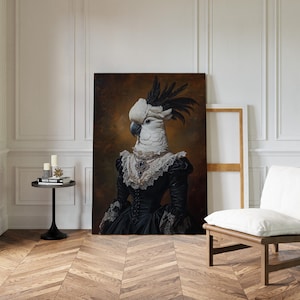 May include: A large framed portrait of a white cockatoo wearing a black dress with lace trim and a jeweled necklace. The bird has a black crest and is set against a dark, blurred background. The room has a wooden floor and white walls.