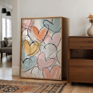 May include: A framed art print featuring a pattern of colorful hearts in shades of yellow, orange, pink, and blue, outlined in black. The artwork is displayed in a room with a wooden cabinet and a patterned rug.