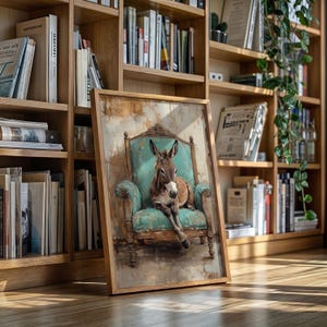 May include: A framed artwork showing a donkey seated in a teal armchair. The donkey is brown and white, with long ears and a relaxed posture. The armchair has ornate details and is set against a textured background. The frame is made of light-coloured wood.