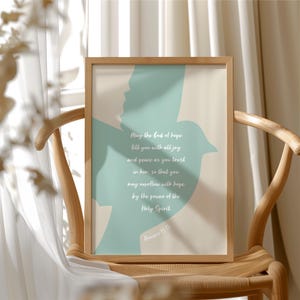 May include: A framed print with a light wood frame. The artwork features a teal silhouette of a bird and a person, with text in white script. The text reads "May the God of hope fill you with all joy and peace as you trust in him..." Romans 15:13.