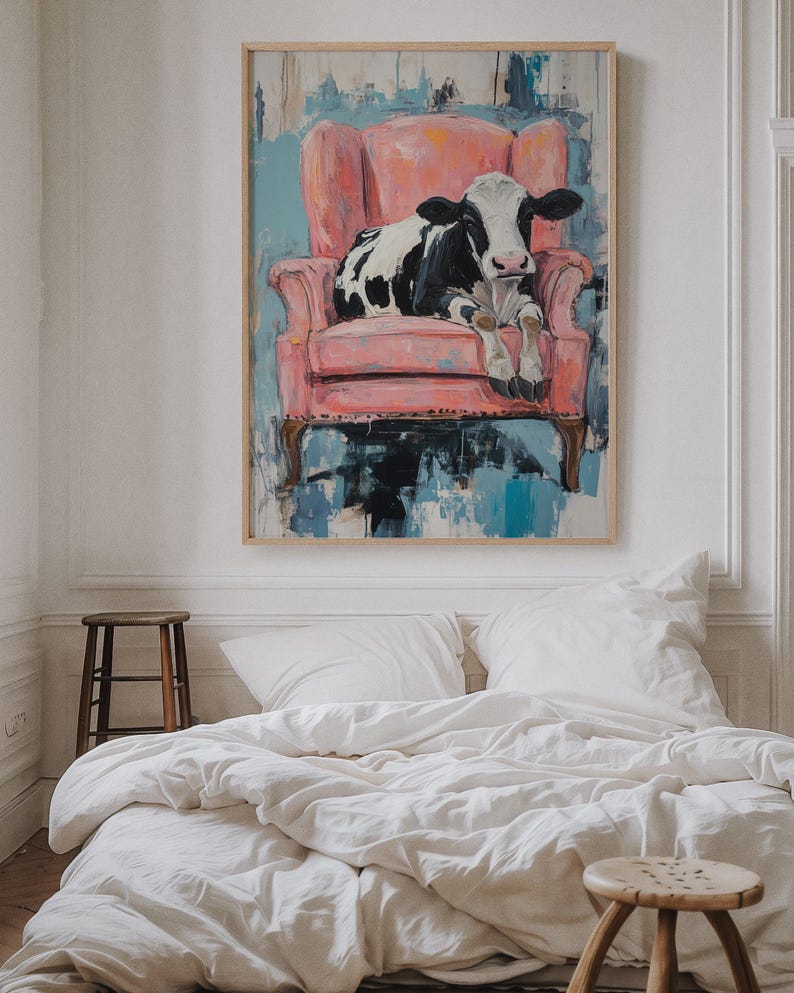 Puede incluir: Una vaca negra y blanca sentada en un sill&oacute;n rosa. El sill&oacute;n est&aacute; frente a una pintura abstracta azul y blanca.
