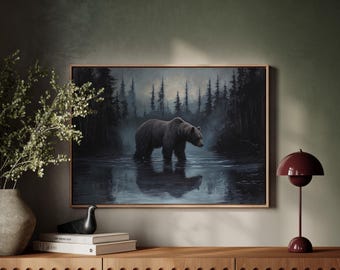 以下が含まれることがあります： 水の中にいるハイイログマが描かれた額入りの絵画。背景には森が描かれています。アートワークは木製のフレームに入っており、緑色の壁に掛けられています。花瓶、本、ランプが置かれた木製のキャビネットが手前にあります。