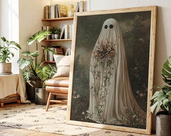 May include: A framed art print featuring a ghost-like figure draped in white fabric, holding a bouquet of flowers. The artwork has a vintage aesthetic, with a soft color palette and a natural background. The ghost has two black eyes.