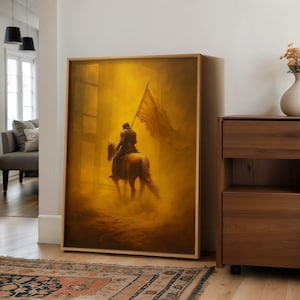 Könnte beinhalten: Ein gerahmtes Kunstwerk zeigt eine Figur auf einem Pferd, die eine Flagge hält, vor einem goldenen, dunstigen Hintergrund. Das Kunstwerk hat eine warme Farbpalette, wobei Gelb- und Brauntöne dominieren. Das Kunstwerk wird in einem Raum mit Holzmöbeln und einem gemusterten Teppich ausgestellt.