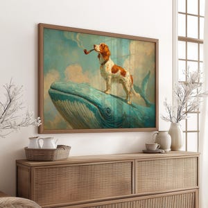 May include: A framed art print depicts a dog with brown and white markings, smoking a pipe while standing on a blue whale. The artwork has a vintage aesthetic with a brown wooden frame and a cloudy sky background. The print is displayed above a wooden cabinet.