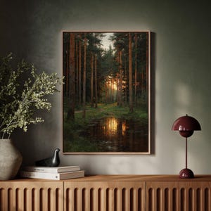 May include: A framed landscape painting shows a forest scene with tall trees and a path leading to a bright, sunlit clearing. The water reflects the sunlight. The painting is displayed above a wooden cabinet with decorative details.