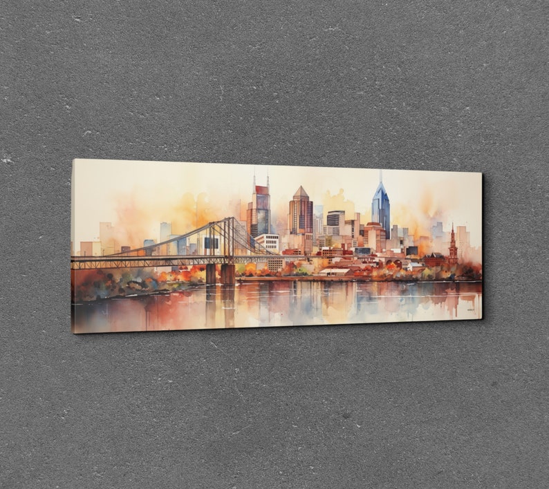 Op de afbeelding: Een aquarel schilderij van een skyline met een brug op de voorgrond. De gebouwen zijn in tinten bruin, oranje en geel, en de lucht is zachtblauw. Het water is diepblauw, en er zijn reflecties van de gebouwen in het water.