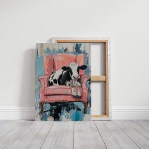 Puede incluir: Una vaca negra y blanca tumbada en un sill&oacute;n rosa. El sill&oacute;n tiene un respaldo alto y est&aacute; decorado con un estampado floral. La vaca est&aacute; mirando a la c&aacute;mara.