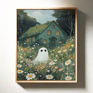 May include: A framed art print depicting a ghost in a field of wildflowers in front of a green house. The house has lit windows and is surrounded by trees. The artwork is presented in a light wood frame.