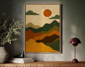 May include: A framed abstract landscape art print featuring a warm color palette. The artwork depicts rolling hills in shades of green, orange, and yellow, with a bright orange sun and green clouds against a beige background. The print is displayed on a wooden cabinet.