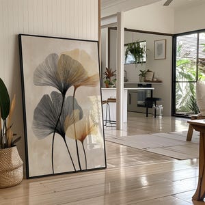 Pode incluir: Grande impressão artística emoldurada com ilustrações botânicas estilizadas em tons de cinza, bege e laranja sobre um fundo neutro. A obra de arte é exibida em um ambiente interno moderno, encostada em uma parede.