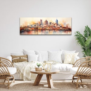 Op de afbeelding: Een aquarel schilderij van een skyline met een brug op de voorgrond. De gebouwen zijn geschilderd in tinten bruin, oranje en geel, en het water is diepblauw. Het schilderij is ingelijst en hangt aan een witte muur.