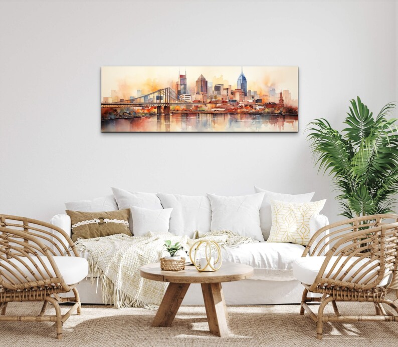 Op de afbeelding: Een aquarel schilderij van een skyline met een brug op de voorgrond. De gebouwen zijn geschilderd in tinten bruin, oranje en geel, en het water is diepblauw. Het schilderij is ingelijst en hangt aan een witte muur.