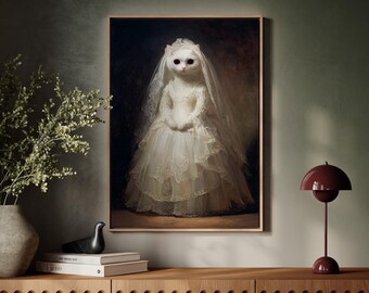 May include: A framed portrait of a cat dressed in a vintage white wedding gown and veil. The cat has red eyes and is posed in a formal portrait style. The artwork is displayed on a wooden cabinet with a modern lamp.