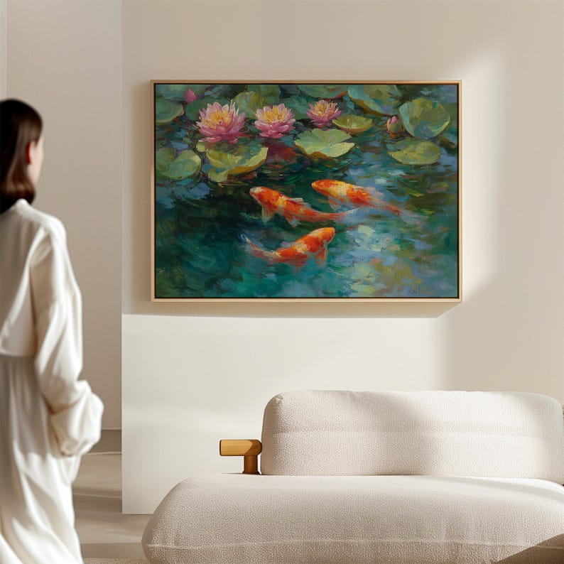 May include: A framed painting depicts a serene pond scene. Pink water lilies bloom among green lily pads. Three orange and white koi fish swim in the turquoise water. The artwork is displayed on a neutral-colored wall.