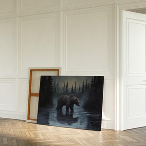Op de afbeelding: Een olieverfschilderij toont een grizzlybeer die in het water staat, met een donker bos op de achtergrond. Het kunstwerk wordt op de vloer tentoongesteld, leunend tegen een houten frame. De sc&egrave;ne speelt zich af in een kamer met witte muren en een houten vloer.