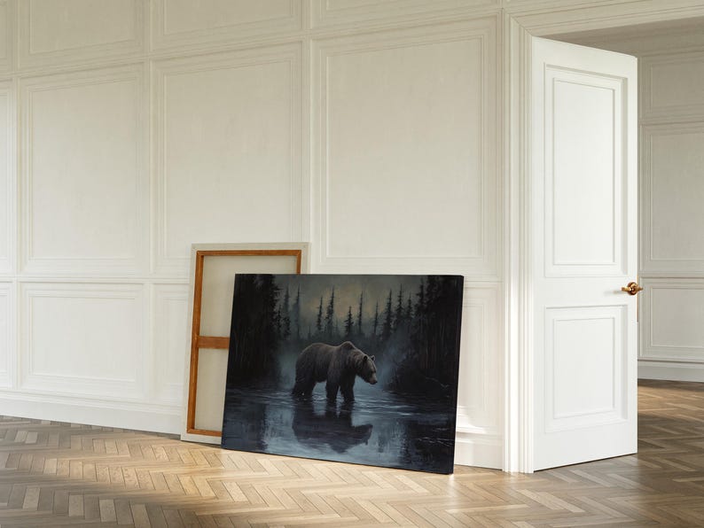Op de afbeelding: Een olieverfschilderij toont een grizzlybeer die in het water staat, met een donker bos op de achtergrond. Het kunstwerk wordt op de vloer tentoongesteld, leunend tegen een houten frame. De sc&egrave;ne speelt zich af in een kamer met witte muren en een houten vloer.