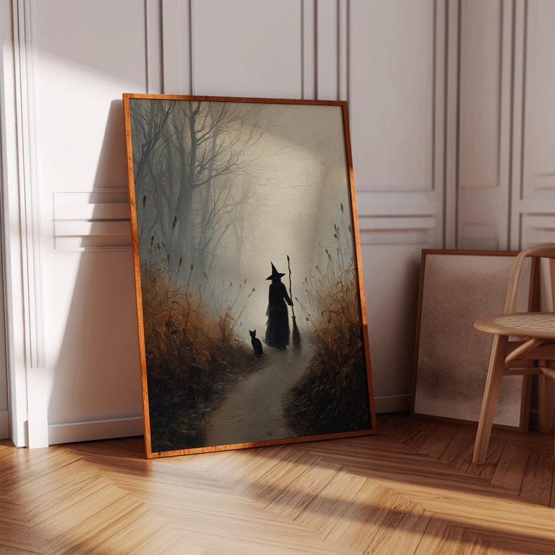 May include: Framed art print depicting a witch walking down a path with a black cat. The artwork features a witch in a black cloak and hat, holding a broom. The path is surrounded by tall grass and trees, creating a mystical, autumnal scene.