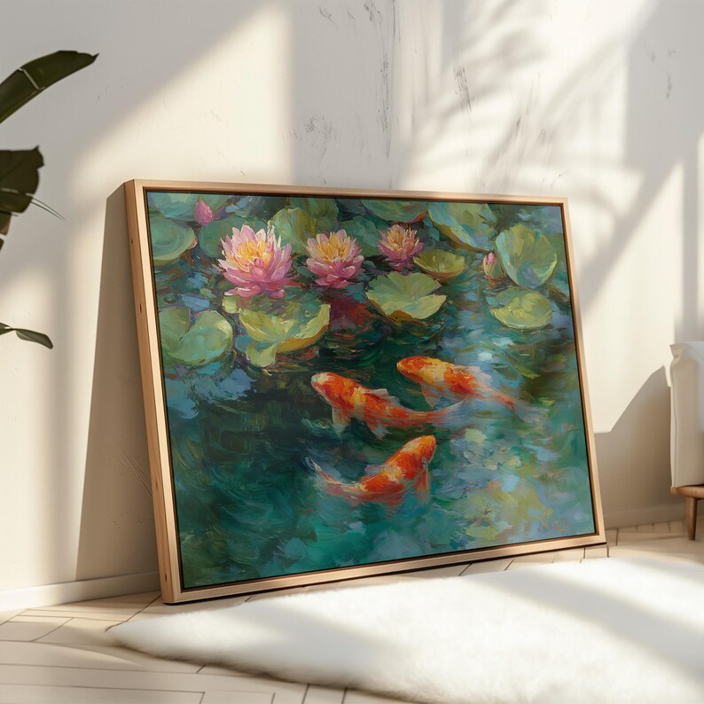 May include: A framed painting depicts a pond scene with koi fish and water lilies. The artwork features orange and white koi swimming in teal water, surrounded by green lily pads and pink and yellow water lilies. The frame is a light wood color.