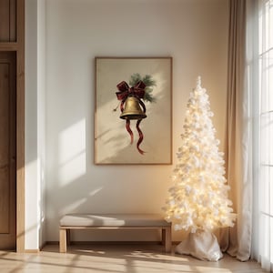 Può includere: Una stampa incorniciata con una campana dorata con fiocco e nastri rossi, accentuata da rametti verdi. Un albero di Natale bianco con luci si trova accanto a una panca di legno. La scena è in una stanza ben illuminata.