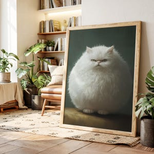 May include: A framed print featuring a fluffy white cat with a stern expression. The cat is centered against a dark green background, with a wooden frame. The image is displayed in a well-lit room with plants and books.