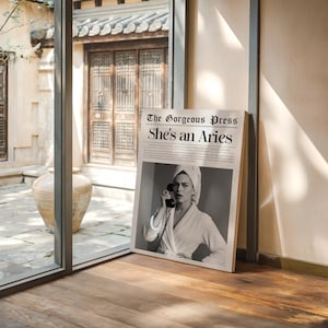 Peut inclure: Une impression encadrée avec une image en noir et blanc d'une femme en serviette et peignoir, tenant un téléphone. Le titre de l'impression est "The Gorgeous Press She's an Aries."