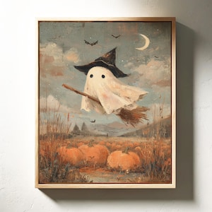 May include: A framed painting of a Halloween scene. A ghost in a witch's hat flies on a broom over pumpkins. The artwork uses a muted colour palette, with a crescent moon and bats in the sky.