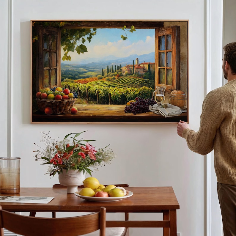 K&ouml;nnte beinhalten: Ein gerahmtes Gem&auml;lde, das eine Fensteransicht einer Weinbergslandschaft mit einem kleinen Dorf in der Ferne zeigt. Das Fenster ist ge&ouml;ffnet und auf der Fensterbank liegen Trauben, Fr&uuml;chte und ein Glas Wein.