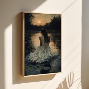 May include: A painting of a woman in a white dress sitting in a body of water with lily pads. The woman is facing away from the viewer and the setting sun is in the background.