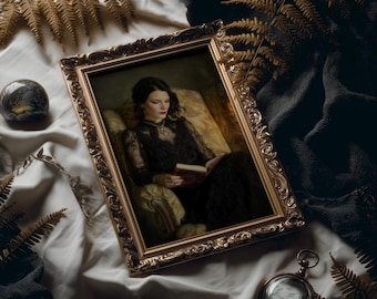 May include: A framed portrait of a woman in a black dress reading a book, set against a backdrop of gold-toned ferns and draped fabric. The ornate gold frame adds a vintage aesthetic. A pocket watch and a decorative stone are also present.