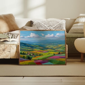 May include: A framed landscape painting depicts a vibrant valley scene. The artwork features rolling hills with fields of green, yellow, and red, under a blue sky with fluffy white clouds. The painting is in a wooden frame.