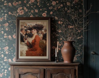May include: A framed vintage painting of a woman in a red dress and hat, holding a glass, is displayed on a wooden cabinet. The cabinet is against a floral wallpaper. A terracotta vase with branches and two lit candles complete the scene.