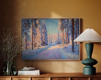 Puede incluir: Pintura enmarcada de un paisaje nevado con altos árboles cubiertos de nieve que bordean un camino. La obra de arte utiliza azules, morados y blancos, con una luz cálida y dorada. Una lámpara turquesa y un mueble de madera están en primer plano.