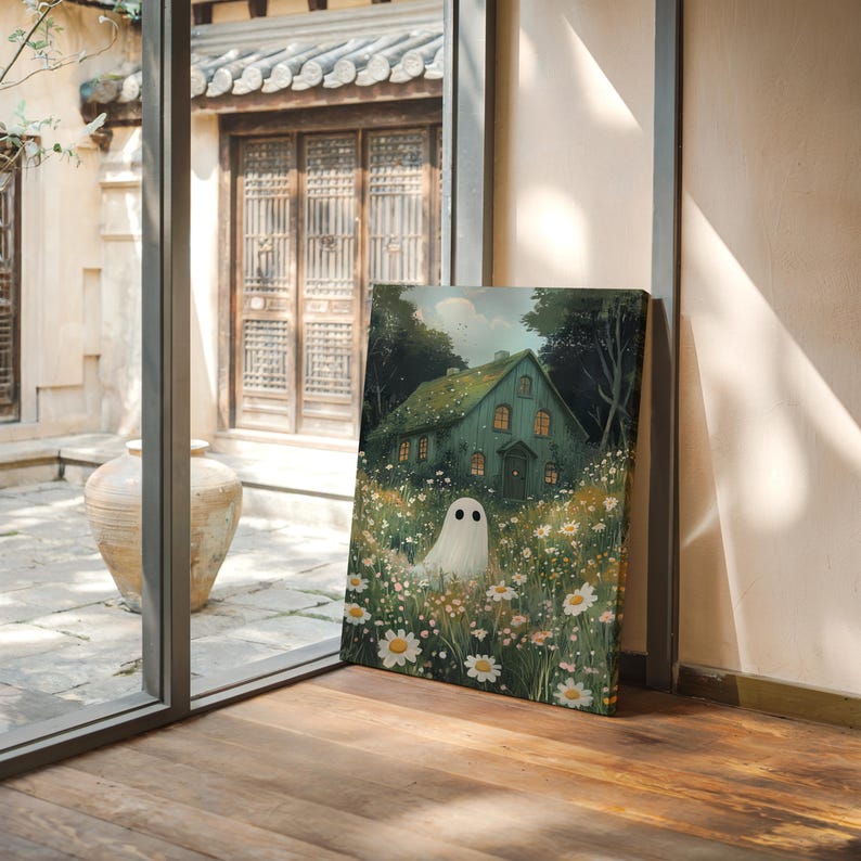 May include: A canvas print depicting a green house with lit windows, set in a field of daisies, with a ghost figure in the foreground. The artwork has a soft, painterly style and is set against a backdrop of trees. The image evokes a whimsical, fairytale atmosphere.