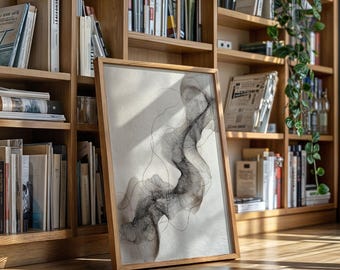 May include: A framed abstract art print featuring a flowing, smoky design in shades of gray and black. The artwork is displayed in a natural wood frame, leaning against a bookshelf filled with books. The print's design has a delicate, linear quality.
