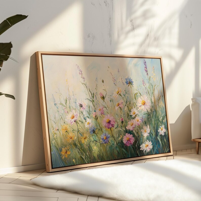 May include: A framed floral painting featuring a field of colorful wildflowers. The artwork showcases a variety of blooms in shades of pink, yellow, blue, and white, set against a backdrop of green foliage and a light blue sky. The painting is displayed in a natural wood frame.