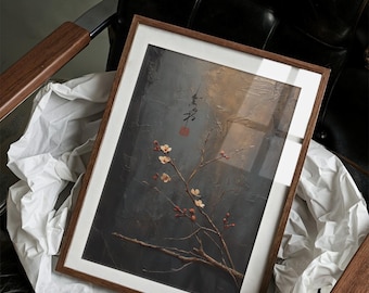 May include: A framed artwork depicting a branch with small white and red flowers against a dark, textured backdrop. The artwork is in a wooden frame with a white mount. The image rests on white paper inside a dark leather chair.