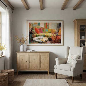 May include: A cozy living room scene featuring a framed painting of a colorful sofa with patterned cushions. A wooden cabinet, a white armchair with a floral pillow, and a coffee table with a cup and saucer complete the inviting space.