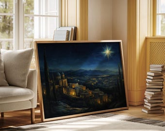 May include: A framed art print depicts a nighttime cityscape with illuminated buildings and a bright star in the sky. The artwork, in a wooden frame, leans against a wall in a room with a neutral-toned rug and a stack of books.