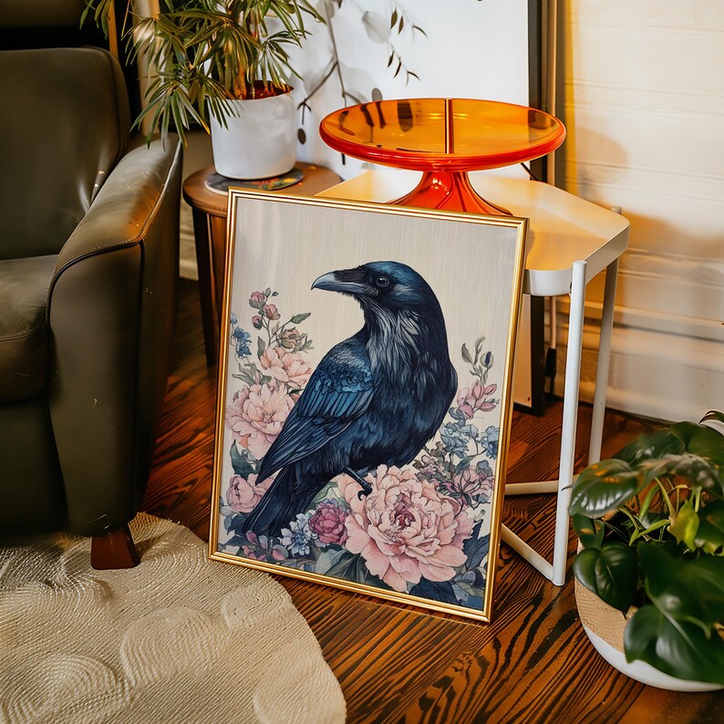 May include: A framed art print featuring a dark blue raven perched amidst pink and blue floral blooms. The raven has detailed feather textures and a sharp beak. The artwork is set in a gold frame, adding a touch of elegance to the nature-inspired scene.