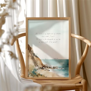 Könnte beinhalten: Ein gerahmter Druck mit einer Aquarelldarstellung einer Strand- und Ozeanszene. Das Kunstwerk enthält ein Zitat in eleganter Schrift. Der Rahmen besteht aus hellem Holz, und der Druck wird auf einem Holzstuhl präsentiert.