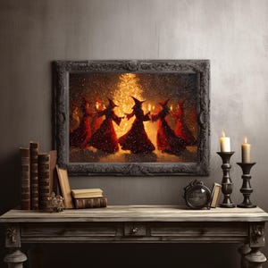 Puede incluir: Una obra de arte enmarcada representa figuras con túnicas rojas y sombreros puntiagudos bailando en círculo alrededor de una fuente de luz central. El marco oscuro y ornamentado rodea la imagen, que está colocada contra una pared neutra. La escena evoca un tema místico o de fantasía.