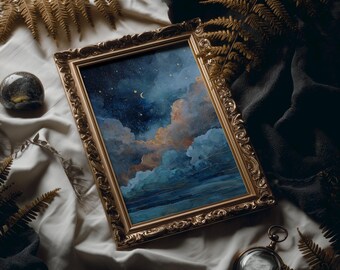 Puede incluir: Una pintura enmarcada de un cielo nocturno con nubes en tonos azules, naranjas y blancos. El marco dorado adornado descansa sobre una tela blanca, con una tela gris oscura en el fondo. También se ven una pequeña piedra oscura y un reloj de bolsillo.